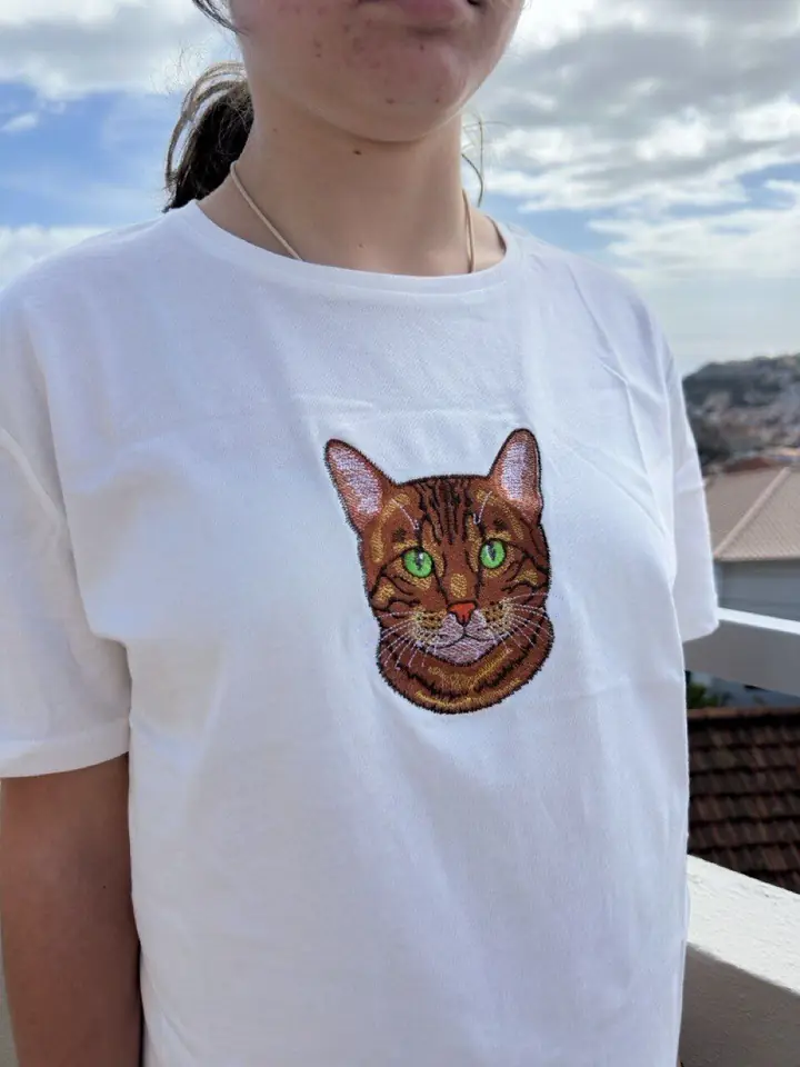 Fundadora da Embroidery Madeira com uma t-shirt bordada com o retrato de um gato, com vista para o Funchal